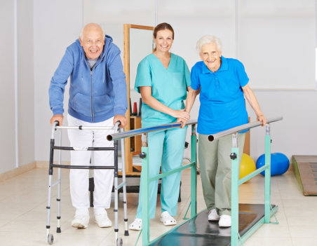 Two senior people doing walking exercise in physiotherapy with physiotherapist