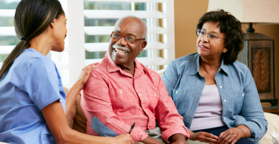 caregiver talking to two elderly