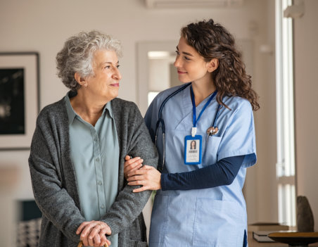 caregiver guiding a senior in walking